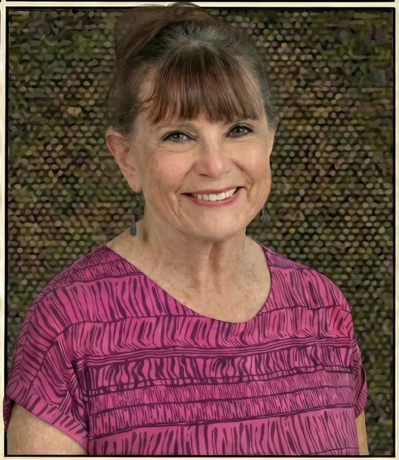 A photo of Annie Elliot wearing a deep pink top against a textured background.